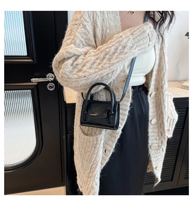 Gros plan d'un mini sac bandoulière en cuir noir avec poignées rondes et design structuré