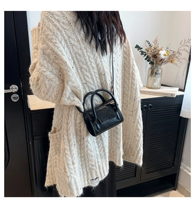 Mini sac bandoulière en cuir noir porté avec un gilet en maille épaisse et texturée
