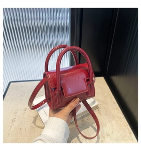Détail du mini sac à main rouge brillant montrant la texture en cuir verni et la poignée