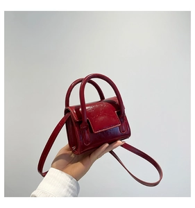 Gros plan détaillé d'un mini sac à main rouge en cuir verni montrant sa taille micro