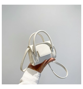 Vue détaillée d'un mini sac carré blanc avec poignées supérieures et fine bandoulière