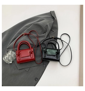 Détail de mini sacs bandoulière en rouge et noir sur une veste de costume grise