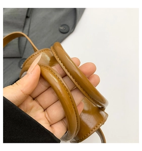 Détail d'un sac à main en cuir marron avec poignée cylindrique et coutures fines