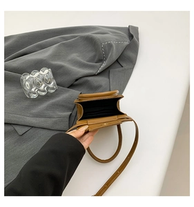 Vue intérieure du mini sac bandoulière en cuir marron montrant la doublure et la sangle