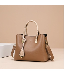 Close-up of brown pebbled leather tote with crocodile pattern handles and gold hardware