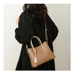 Detailed shot of brown pebbled tote bag with crocodile charm and golden hardware