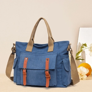 Close-up of navy canvas tote bag with brown straps and vintage buckle pocket detail
