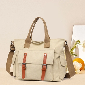 Detail of beige canvas tote bag with brown straps and vintage buckle flap pocket