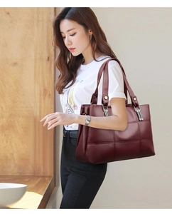 Detail of wine red tote bag with quilted stitching and lychee pattern faux leather texture