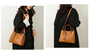 Detail of tan leather tote bag with lychee texture and gold metal logo charm