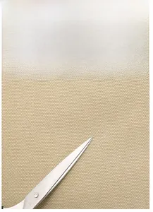 Detail of durable beige canvas fabric texture with scissors showing material strength