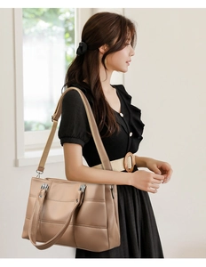 Detail of khaki PU leather tote bag with geometric quilting and wide woven shoulder strap