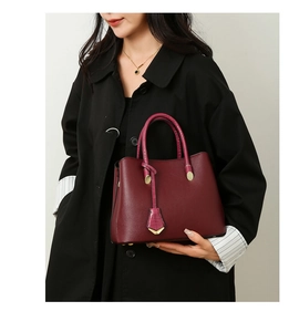 Detail of burgundy lychee grain tote bag with round handles shown with elegant model