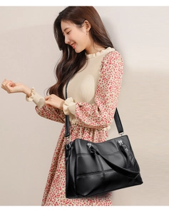 Close-up of black PU leather tote bag featuring lychee texture and criss-cross stitching