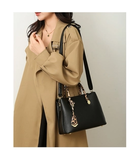 Close-up of black pebble leather tote with leopard scarf handle and gold hardware detail