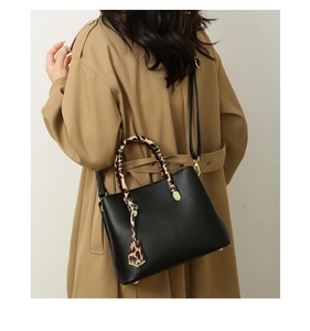 Detail of black pebbled leather tote bag featuring leopard print handles and shoulder strap