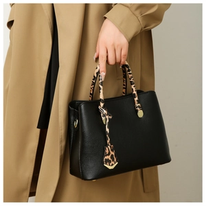 Detail of black lychee grain tote bag with leopard print handle and golden metal buckle