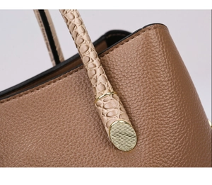 Detail of brown lychee leather tote with beige croc-embossed handle and gold hardware