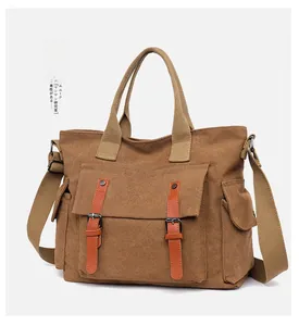 Close-up of brown canvas tote bag featuring leather buckles and detachable shoulder strap