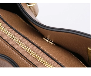 Close-up of brown litchi grain leather tote bag with gold zipper and precise stitching