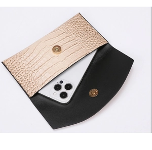 Detail view of champagne crocodile embossed clutch bag with magnetic snap and phone compartment