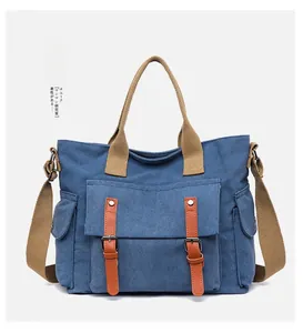 Detailed shot of blue canvas tote bag with brown leather buckles and woven straps