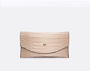 Detail of beige crocodile embossed envelope clutch bag with gold metallic button
