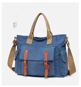 Detail view of multi-pocket canvas tote bag in vintage denim blue with khaki straps