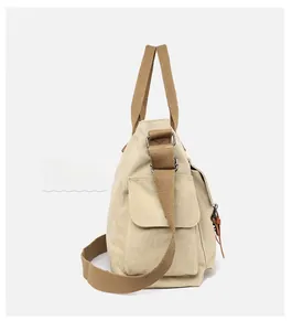 Side view of beige canvas tote bag with brown straps and functional side pockets