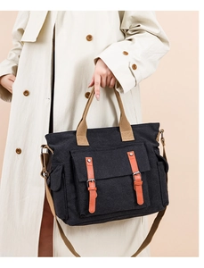 Detail of black canvas messenger bag with orange leather trim and front flap pockets