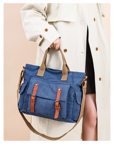 Detailed view of navy canvas crossbody bag with brown leather straps and side pockets