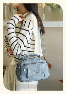 Detail view of light blue soft leather crossbody bag with multi-pocket and kangaroo logo