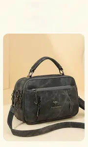 Detail of dark grey vintage canvas handbag featuring multiple zippers and a metal kangaroo logo