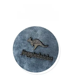Detail shot of the blue denim texture and the kangaroo metal logo on the handbag