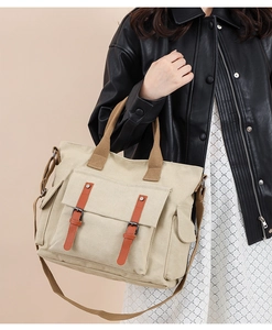 Close-up of beige canvas crossbody tote with leather buckle pocket and shoulder strap