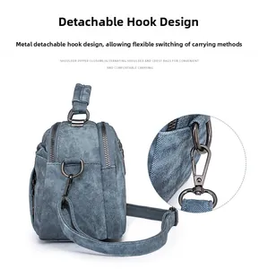 Detail of detachable gun-black metal hook on blue denim textured multifunctional bag