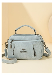 Close-up of light blue textured shoulder bag with kangaroo logo and multiple pockets