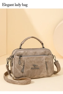Detail view of khaki textured crossbody bag with metal logo and adjustable strap