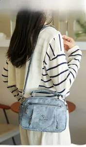 Detail of light blue textured shoulder bag featuring kangaroo logo and metallic zipper