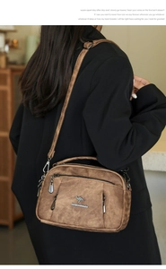 Brown vintage textured crossbody bag with metal kangaroo logo on a soft leather surface