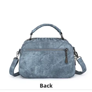Detail view of the back of this denim textured women's bag showing zippers and straps