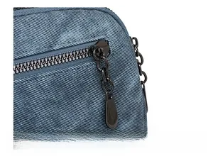 Detailed close-up of premium black metal zipper on textured blue denim shoulder bag
