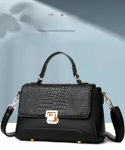 Detailed view of crocodile embossed leather texture and gold metal twist lock on black handbag