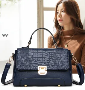 Close-up of deep blue handbag with crocodile texture flap and gold hardware lock