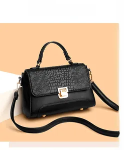 Detail of black handbag showing crocodile-textured flap and golden metal clasp lock