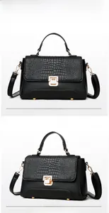 Detail of black crocodile texture handbag with golden twist lock and soft leather finish