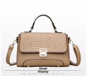 Detail of khaki handbag featuring crocodile texture flap and gold hardware lock closure