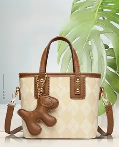 Detail of quilted beige bucket bag with brown puppy charm and golden hardware