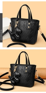 Detail of black pebbled leather bucket bag with quilted patterns and a cute dog charm