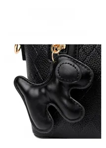 Detail of black quilted leather bucket bag featuring a cute puppy-shaped charm and gold hardware